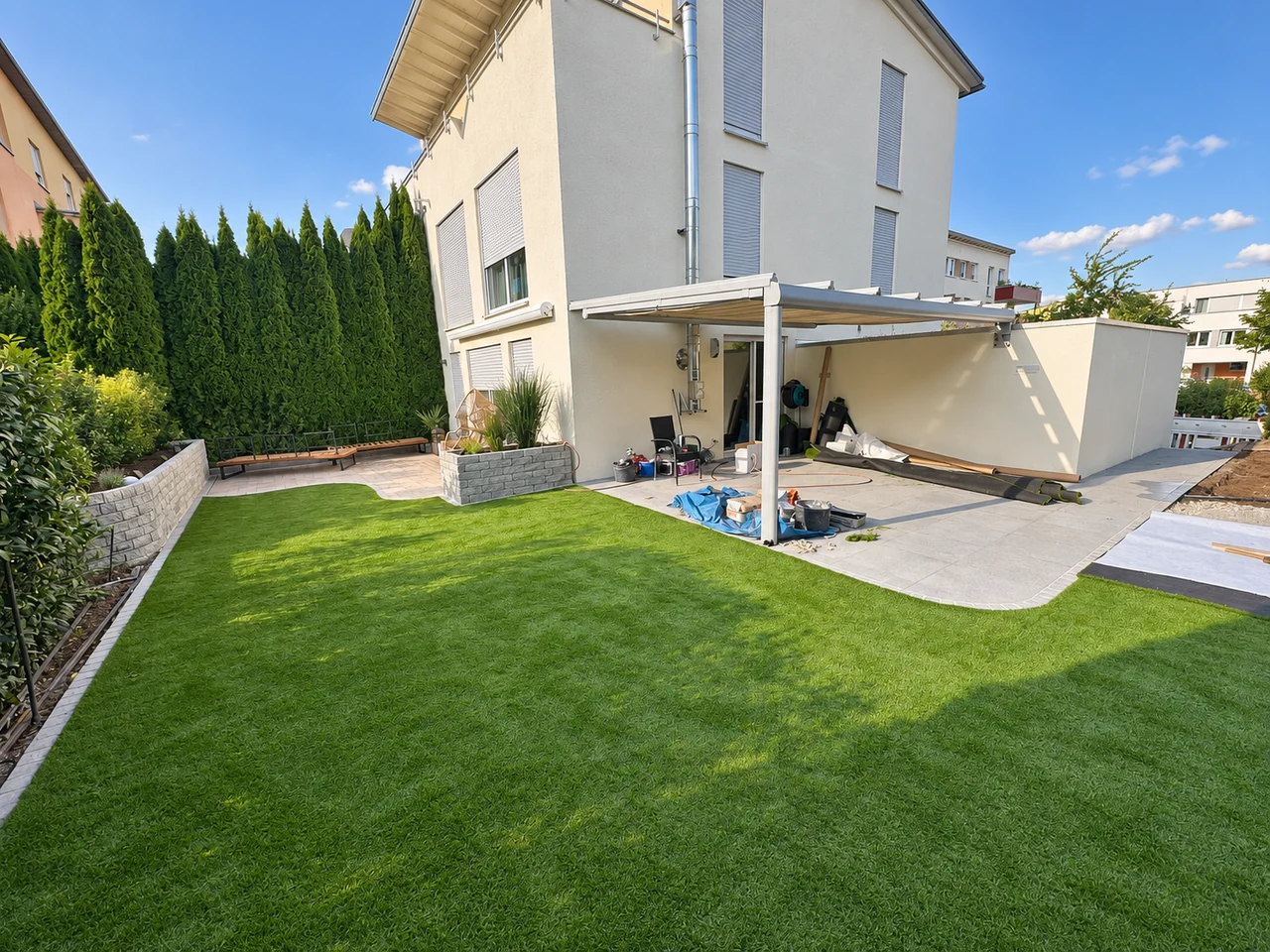 Neu angelegter Garten mit Rasen, Natursteinmauer und überdachter Terrasse